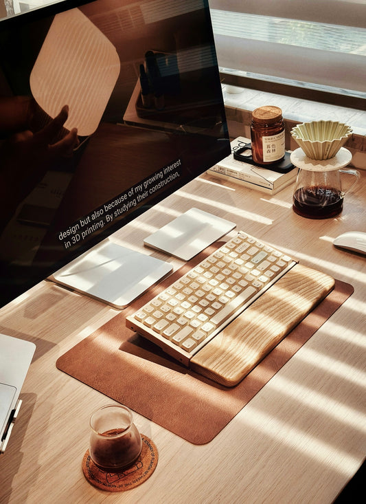 Wooden desk with keyboard, coffee, and monitor.